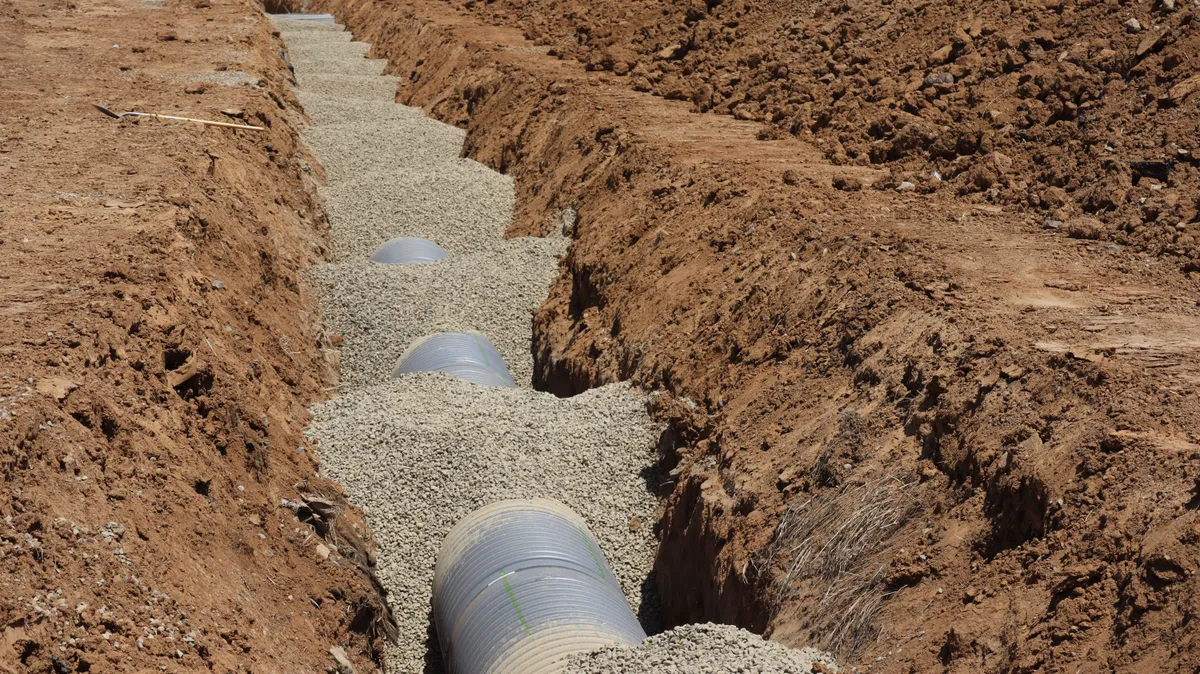 Drain field trench with perforated pipe bedded in gravel during a septic system installation — illustrative stock photo, not an actual Pahrump job site